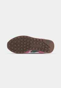 Saucony čības ārējā zole ir izgatavota no gumijas, ar brūnu teksturētu virsmu ar apaļām rakstām, papildināta ar rozā un zaļām akcentiem sānos.