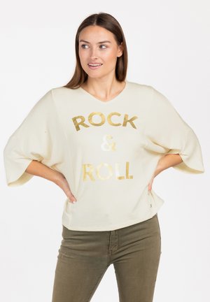 Maglione oversize color crema con scollatura a V e maniche corte. Grafica in foglia d'oro "ROCK & ROLL" sul fronte. Tessuto morbido.