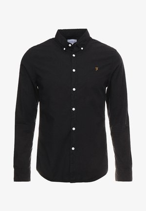 Zwart overhemd met lange mouwen, witte knopen, een button-down kraag en een klein goudkleurig geborduurd logo op de linkerborst.