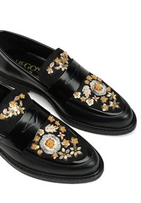 Czarne skórzane loafersy z finezyjnym haftem kwiatowym w złotym, białym i pastelowych kolorach. Teksturowane akcenty i klasyczny design.