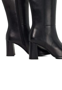 Black knee-high heeled boots made of smooth leather. Features a side zipper, square heels, and a sleek silhouette.