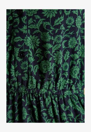 Dunkelblauem Stoff mit grünem Blumenmuster, mit Knöpfen und gerafftem Taillendetail. Weiche Textur mit Blatt- und Blütenmotiven.