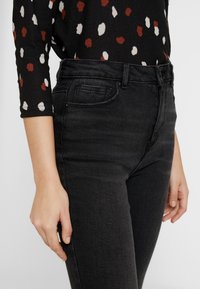 Svarta denimjeans med en figurnära design, med klassisk femficksstil och subtila sömdetaljer. Slät textur, midjehight.