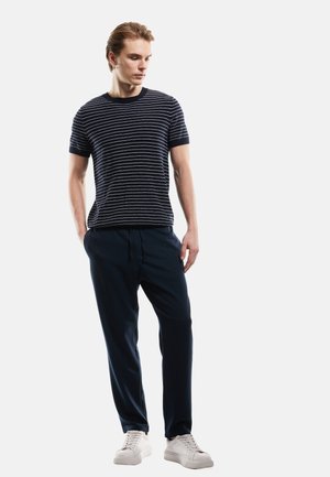 Navy gestreiftes T-Shirt mit kurzen Ärmeln, kombiniert mit navy Jogginghosen und weißen Sneakern. Glatter Stoff, lockere Passform, einfaches Design.