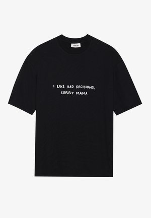 T-shirt en coton noir avec des manches courtes et un col rond. Le texte imprimé en blanc dit : "J'AIME LES MAUVAISES DÉCISIONS, DÉSOLÉE MAMAN."