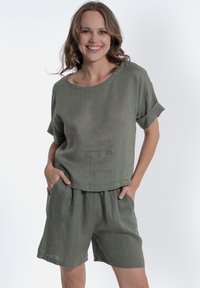Completo in lino verde oliva composto da una maglietta a maniche corte con scollatura ampia e pantaloni corti morbidi con waistband elastico e tasche laterali.