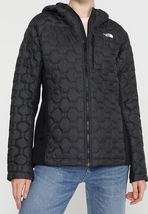 Black insulated jacket with a hexagonal quilted texture, hood, and front zipper. Features side pockets and contrasting black panels.
