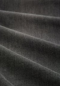 Donkergrijze stof met een gladde textuur, met subtiele weefpatronen en een lichte glans, die gevouwen lagen toont in een close-up.
