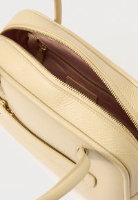 Μπεζ δερμάτινη τσάντα με υφή στην επιφάνεια, με ροζ εσωτερικό και φερμουάρ σε χρυσό τόνο. Πλαϊνή λαβή για εύκολη μεταφορά.