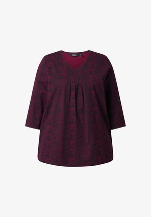 Burgundská tunika se vzorem, s rukávy po tři čtvrtiny, výstřihem do V a sklady na přední straně. Vyrobena z měkké, lehké tkaniny.