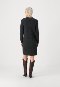 Σκούρο γκρι πλεκτό φόρεμα με μακριά μανίκια, μέτριο μήκος, στρογγυλή λαιμόκοψη και υφή. Συνδυασμένο με καφέ cowboy μπότες με μυτερή μύτη.