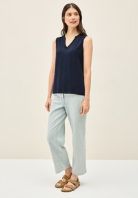 Top senza maniche blu navy con scollo a V, abbinato a jeans corti blu chiaro e sandali marroni con cinturini. Tessuto morbido.