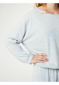 Světlá šedá, dlouhý rukáv, top z měkké texturované látky s volným střihem. Má široký výstřih a jemné drapérie, doplněné elastickým pasem.