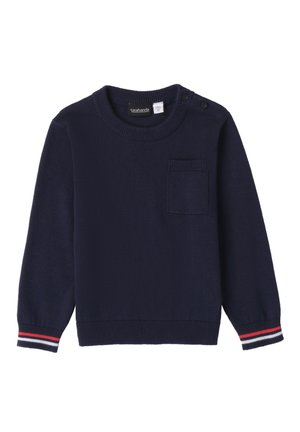 Pull en bleu marine à manches longues, col rond et une poche sur la poitrine gauche. Présente des poignets côtelés rayés en rouge et blanc.