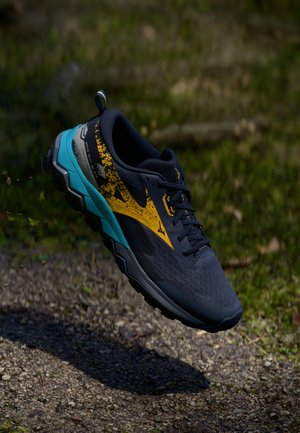 Chaussure de trail running avec une tige texturée bleu marine, des accents jaunes et une semelle turquoise. Présente un design robuste et une semelle extérieure adhérente.