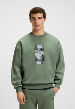 Groene sweatshirt met ronde hals, verlaagde schouders en een grafische print aan de voorkant met "BOSS" tegen een gestructureerde achtergrond. Soepele textuur.