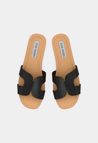 Claquettes noires avec un design en découpes abstraites. Comprend une semelle intérieure beige avec des coutures et une étiquette de logo. Semelle plate pour un usage décontracté.