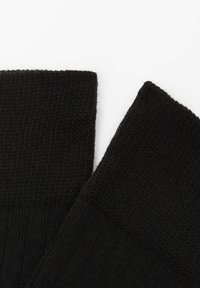 Calcetines negros de punto con una banda superior acanalada, textura suave y acabado liso. El diseño es simple, sin patrones ni acentos.