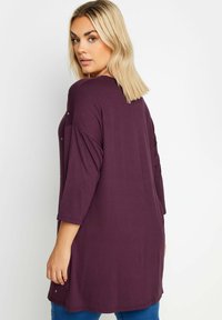 Mörklila långärmad topp i mjukt material med avslappnad passform, som har subtila stjärnornas dekorationer på axlarna och sidslitsar.