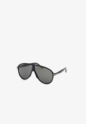Aviator-stil solbriller med en blank sort plastisk ramme og gråtonede linser, med guldfarvede detaljer på stængerne.