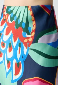 Kleurvolle rok met een bloemenpatroon in rood, blauw, groen en roze accenten op een donkere achtergrond; gemaakt van een zachte, lichtgewicht stof.