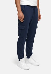 Navy Jogginghosen aus Baumwollmischung, mit elastischem Bund, Seitentaschen und cargoartigen Taschen an den Oberschenkeln.