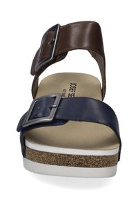 Braune und marineblaue Sandalen mit zwei verstellbaren Riemen, die metallische Schnallen und eine korkstrukturierte Zwischensohle auf einer weißen Gummisohle aufweisen.