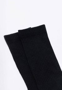 Czarne skarpety ribbed o miękkiej teksturze i ciasno dzianym materiale, z mankietem na górze i bezszwowymi wykończeniami.