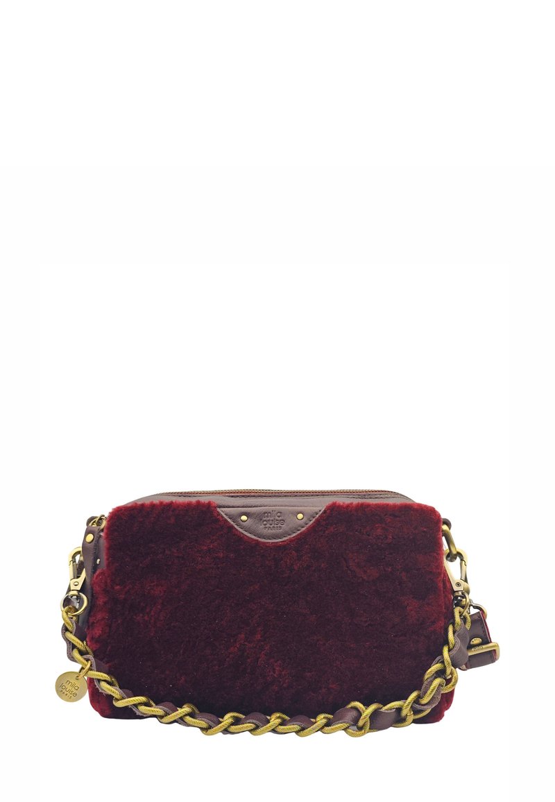 Sac bandoulière en fausse fourrure rouge avec des accents en cuir marron, une chaîne dorée et une fermeture éclair. Présente un patch logo sur le devant.