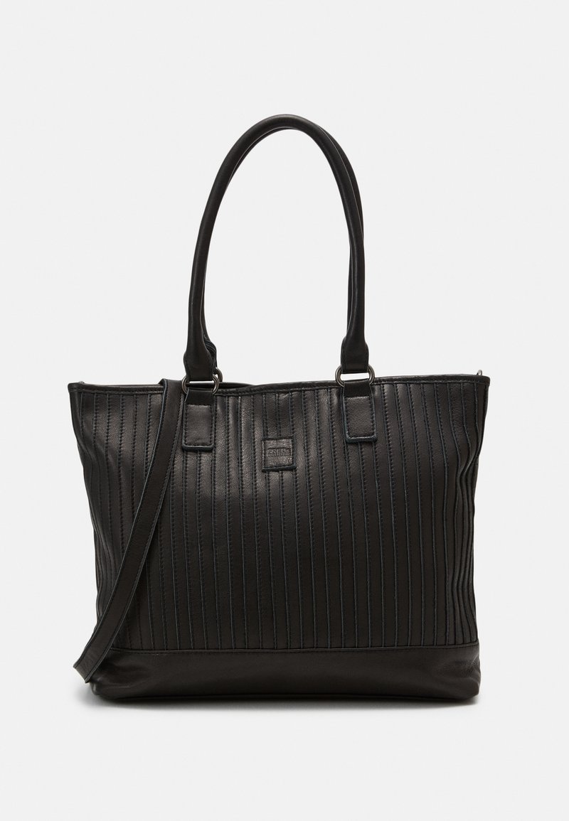 Sac cabas en cuir noir avec couture verticale, deux poignées supérieures, une bandoulière amovible et un petit patch carré avec logo sur le devant.