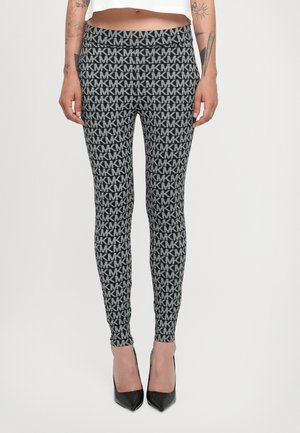 Leggings a fantasia con un design in nero e grigio caratterizzato da ripetuti loghi "MK". Vestibilità slim con vita alta. Indossati con tacchi alti neri.