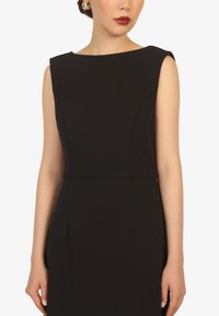 Black sleeveless dress with a boat neckline, structured fit, and clean lines. Made from smooth fabric, minimal seams, and no visible patterns.