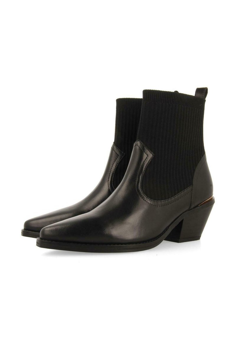 Botines negros de tobillo con puntera afilada, parte superior de cuero, caña de tela acanalada y tacón de bloque de altura media. Incluyen una lengüeta para facilitar su calzado.