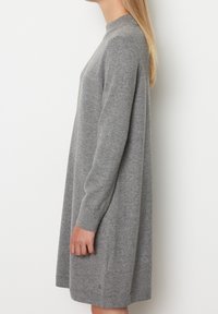 Abito grigio lavorato a maglia con maniche lunghe, colletto alto, vestibilità rilassata e orlo a coste. Texture morbida e design minimalista.