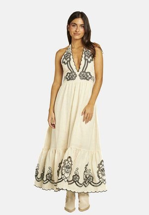 Robe crème à encolure halter avec broderie florale noire. Présente un décolleté en V profond et un ourlet en plusieurs niveaux. Texture lisse, design longueur cheville.