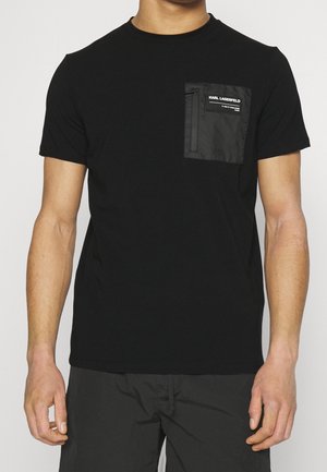 Czarny t-shirt z krótkim rękawem wykonany z bawełny, z czarną kieszenią z nylonu z zamkiem błyskawicznym i detalem logo. Prosty, jednolity design.