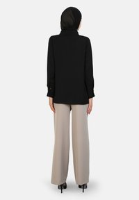 Black long-sleeve top with a collared design, paired with light beige wide-leg trousers, featuring a soft texture and minimalistic style.
