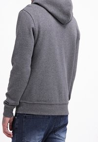 Hoodie aus grauem Fleece mit gerippten Bündchen und Saum, lässige Passform. Enthält eine Kängurutasche und hat eine weiche Textur.