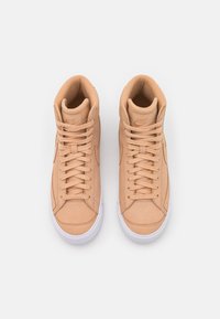 Sneaker alte color tabacco con tomaia in pelle liscia, dotate di lacci piatti, collare imbottito e suola in gomma bianca. Design minimalista, senza pattern.