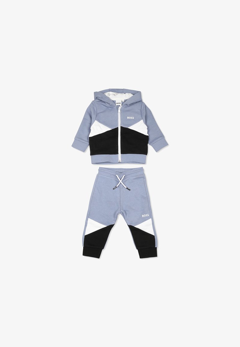 Twee-delige trainingsoutfitset in lichtblauw, bestaande uit een zip-up hoodie met zwarte en witte geometrische accenten en bijpassende sweatpants met drawstring.
