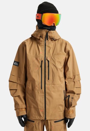 Braune wasserdichte Jacke mit hohem Kragen, mehreren Reißverschluss-Taschen und einem strukturierten Stoff. Verfügt über verstellbare Manschetten und Kapuze.