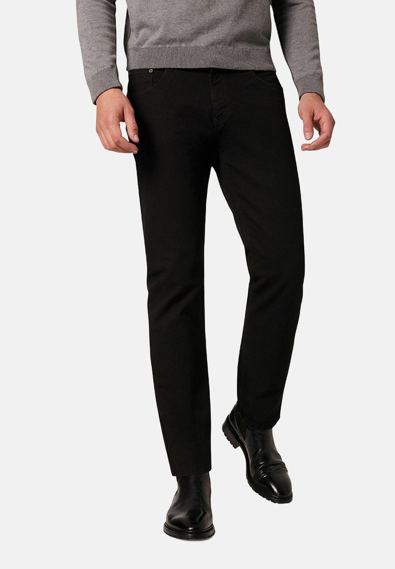 Czarne slim-fit spodnie wykonane z mieszanki bawełny. Posiadają pięć kieszeni i subtelne przeszycia. Połączone z szarym swetrem i czarnymi botkami.