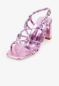 Sandal con tacco metallico rosa, punta quadrata, design con più cinturini e fibbia alla caviglia. Presenta un tacco a blocco per maggiore stabilità.