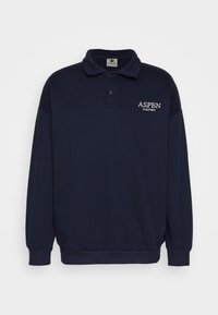 Marinblå tröja med långa ärmar, ribbade muddar och nederkant, knäppbar krage, med "ASPEN"-text i vit brodering på bröstet.