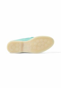 Zapato verde de ante con una suela de goma texturizada que presenta patrones de agarre circulares y una suela exterior beige lisa. Nombre de la marca grabado en el talón.