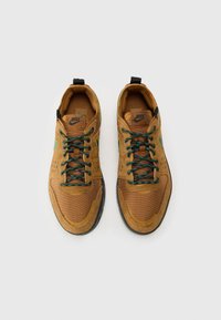 Hnědé tenisky z broušené kůže a síťoviny, s zelenými tkaničkami, perforacemi pro větrání a černou gumovou podrážkou.