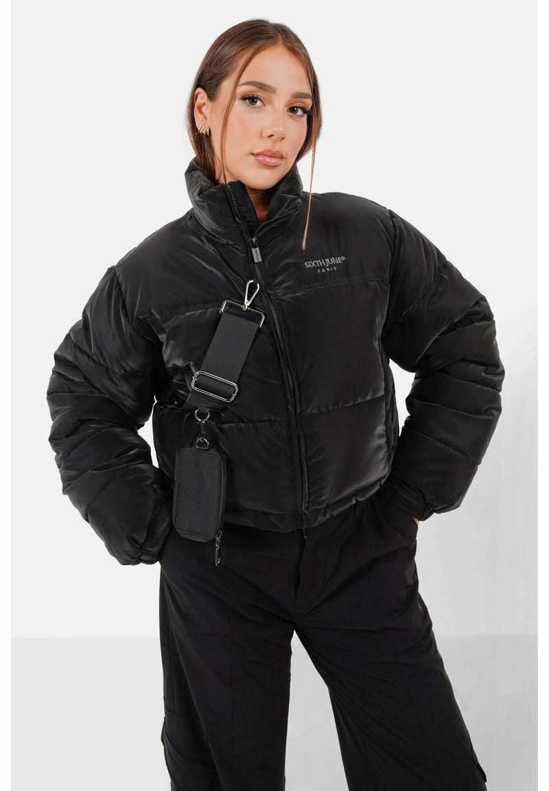 Zwarte pufferjack met een hoge kraag, zijzakken met rits en een afneembare schouderriem. Bevat een logo op de borst.