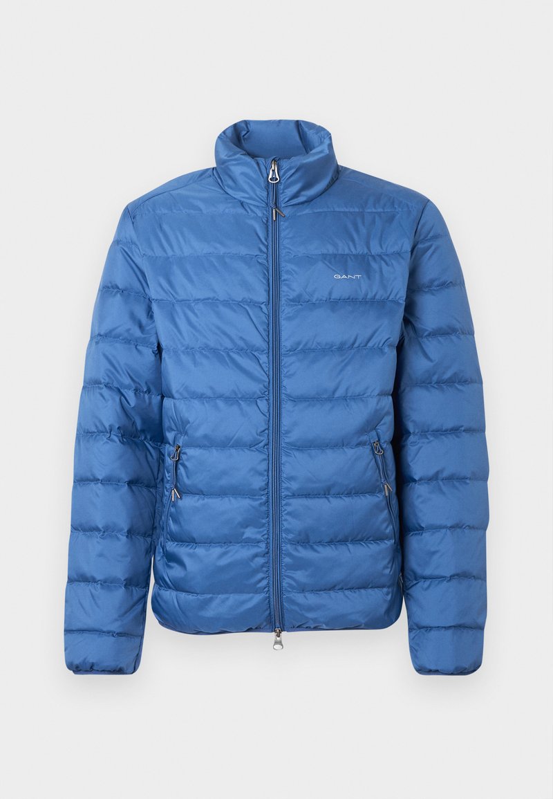 Blue puffer jacket featuring a high collar, horizontal quilted design, front zip closure, and two zippered side pockets.
