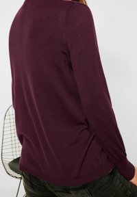 Bordový pletený svetr s dlouhými rukávy, uvolněným střihem a žebrovanými manžetami. Hladký povrch s jemným vzorem na zádech.