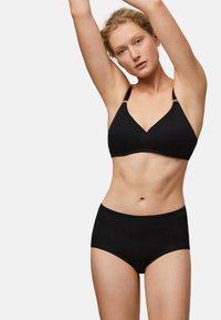 Bralette negro sin costuras con diseño de escote en v y tirantes ajustables, combinado con bragas negras de talle alto con un delicado borde de encaje.